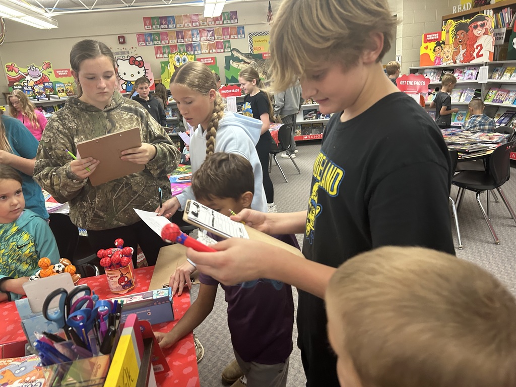 Older students are writing down lists on clipboards. Younger students are making their choices.