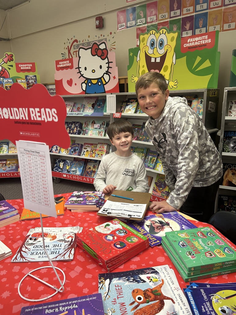 An older student is writing down  a list on the clipboard. A younger student is making a choice.