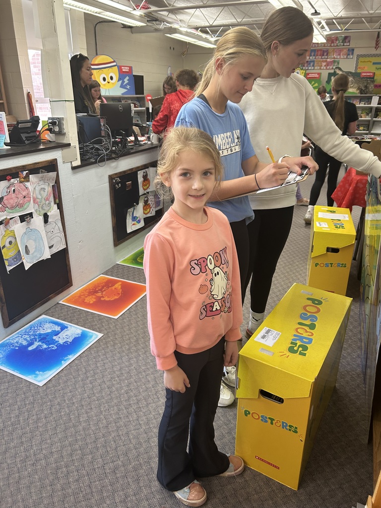 An older student is writing down  a list on the clipboard. A younger student is making a choice.