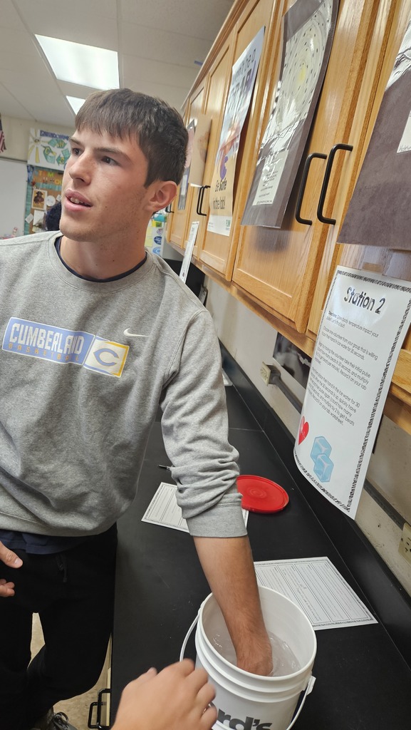 A student is standing with his hand in a bucket of ice water.