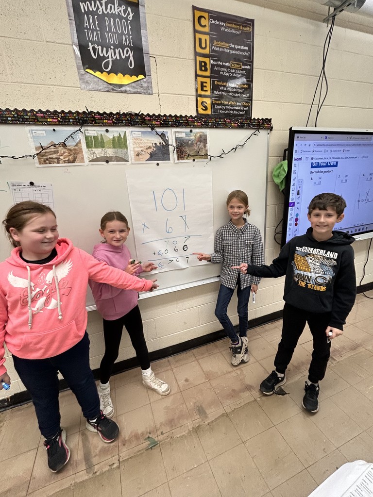 A group is holding up a paper with a math problem that had the answer of 6767.