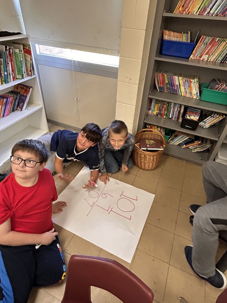 A student issitting on the floor. They are working a math problem.