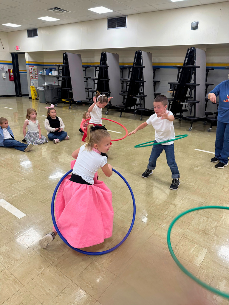 A student is dressed in 50s attire. She is hula hooping.