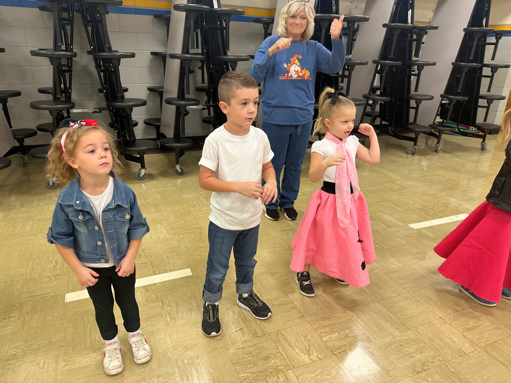 Students are dressed in 50s attire. They are doing 50s dance moves.