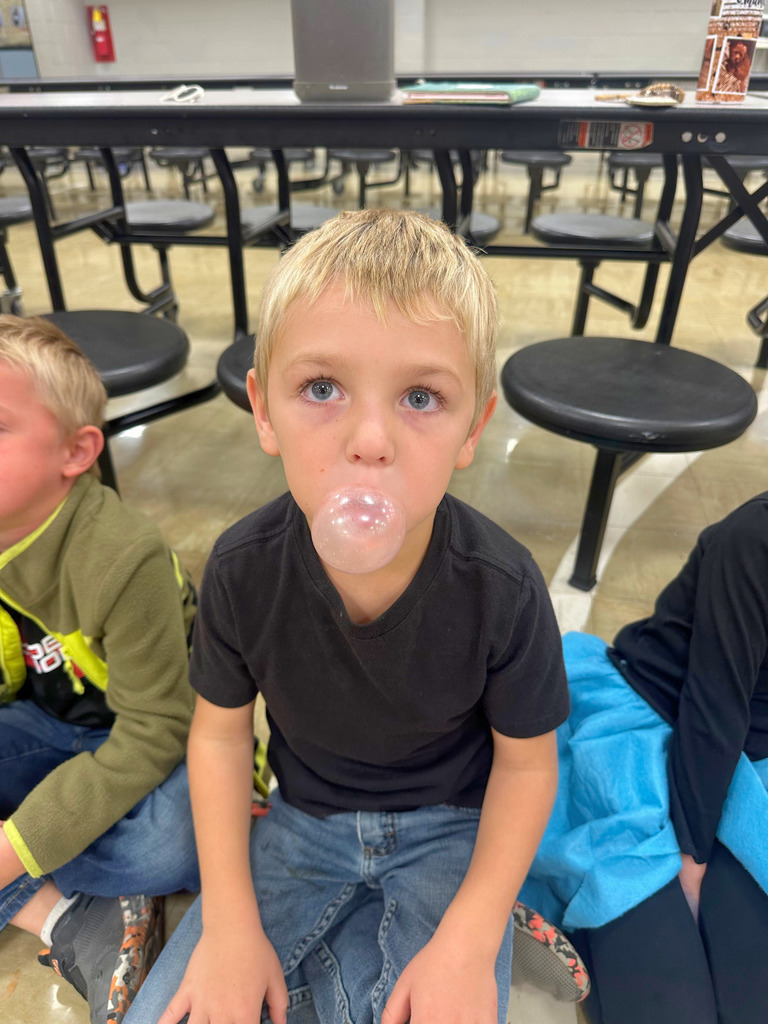 A student is dressed in 50s attire. He is blowing bubble.