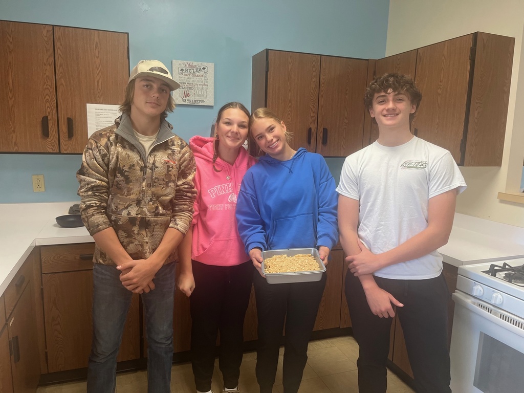 Students are standing side by side. The middle student is holding the pan of apple crisp.
