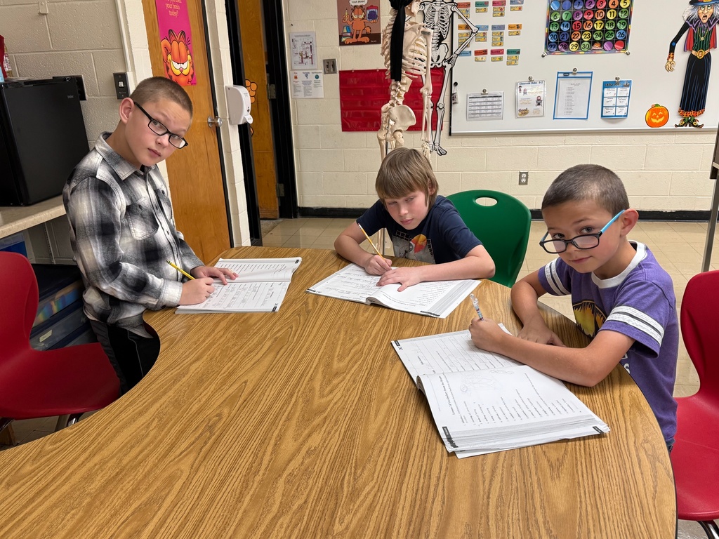 Students are working in a group writing ideas in their books for a fable.