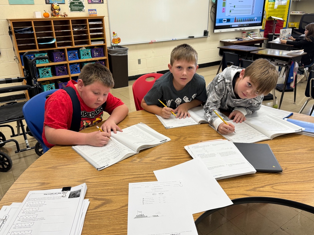 Students are working in a group writing ideas in their books for a fable.