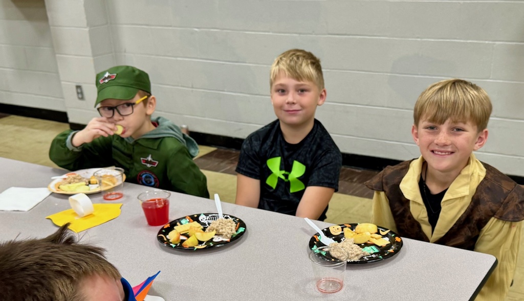 Boys are sitting at a table. They are having a medieval snack.
