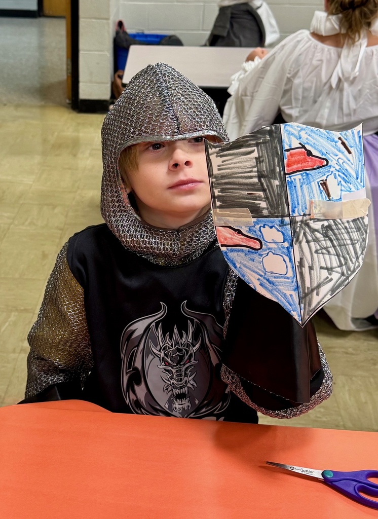 A student is dressed as a knight. He is holding his crest.