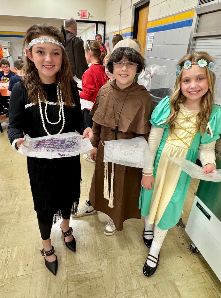 Three students are holding their stained-glass windows. They are dressed up in character.