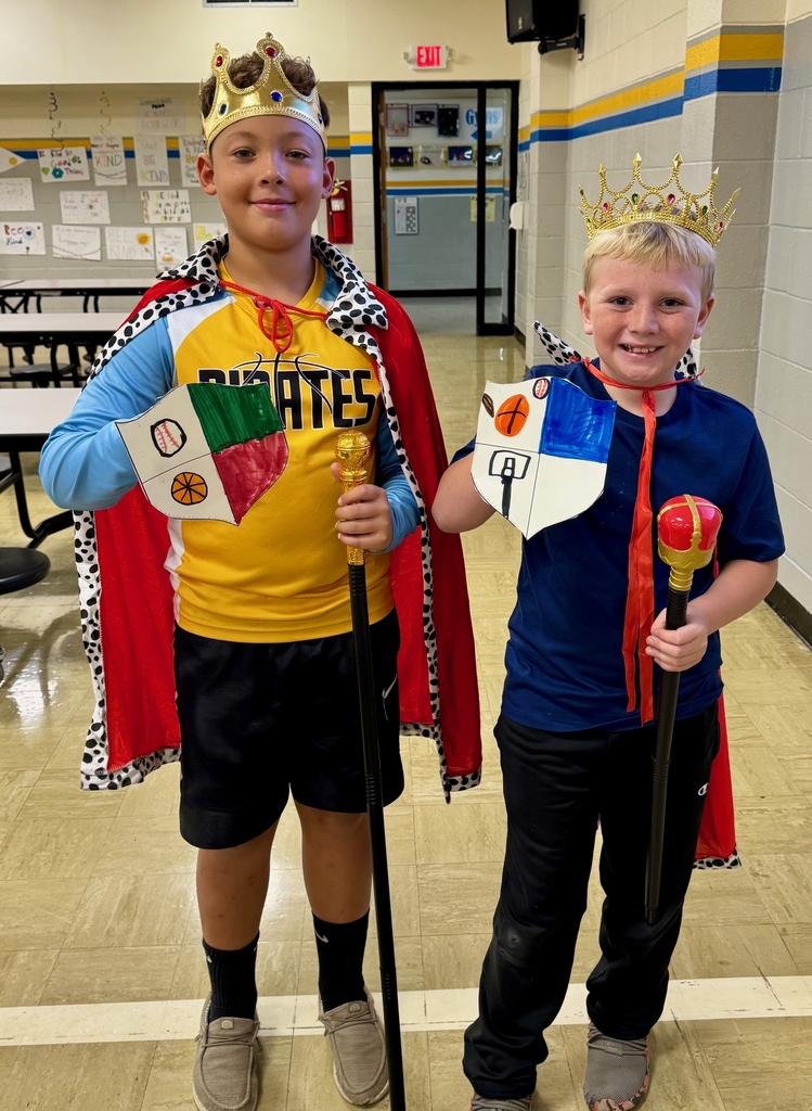 Two students dressed as kings are holding their crests.