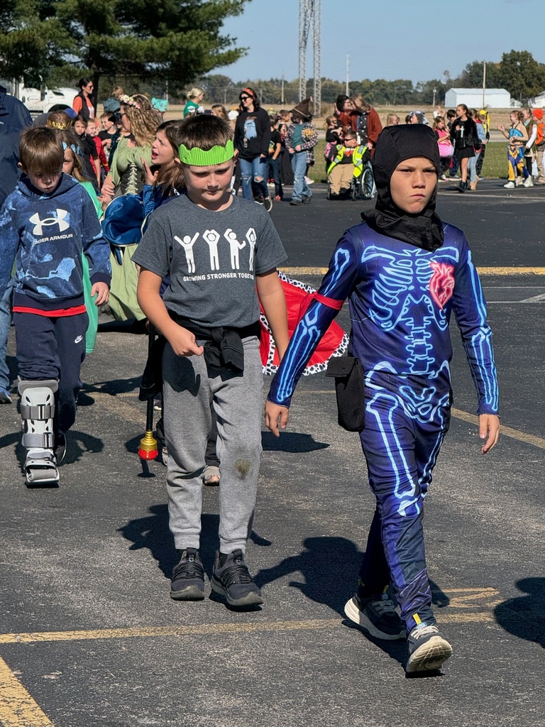 Students and staff are dressed in Halloween costumes and walking in the parade.