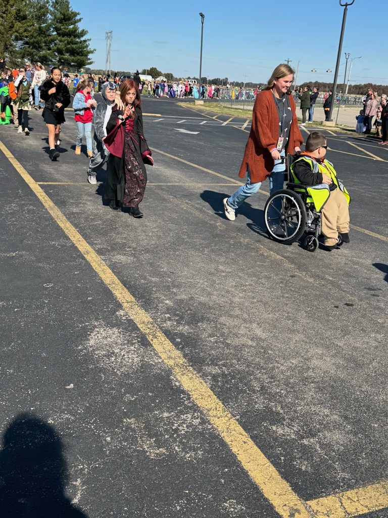 Students and staff are dressed in Halloween costumes and walking in the parade.