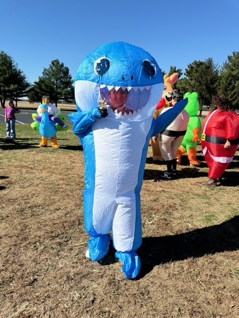 The winner is posing with her trophey. She is in an inflatable Baby Shark costume.