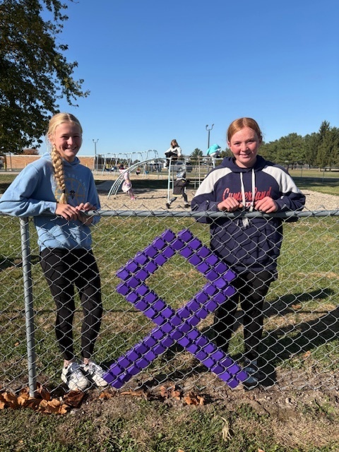 The students are standing by their design. It is a purple ribbon.