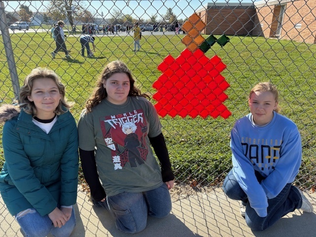 The students are kneeling by their design. It is a pumpkin.