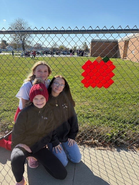 The students are kneeling by their design. It is a pumpkin.