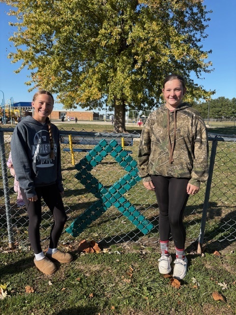 The students are standing by their design. It is a green ribbon.