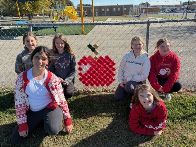 The students are kneeling by their design. It is a red apple with a stem.