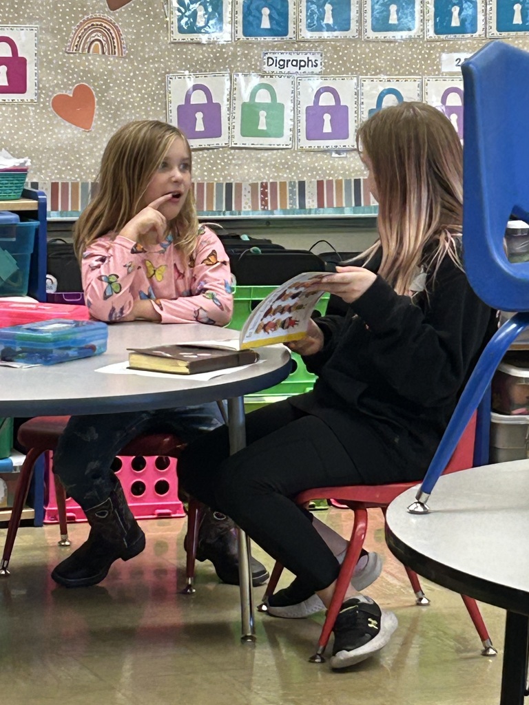 A middle school students is reading a book to a kindergarten student.