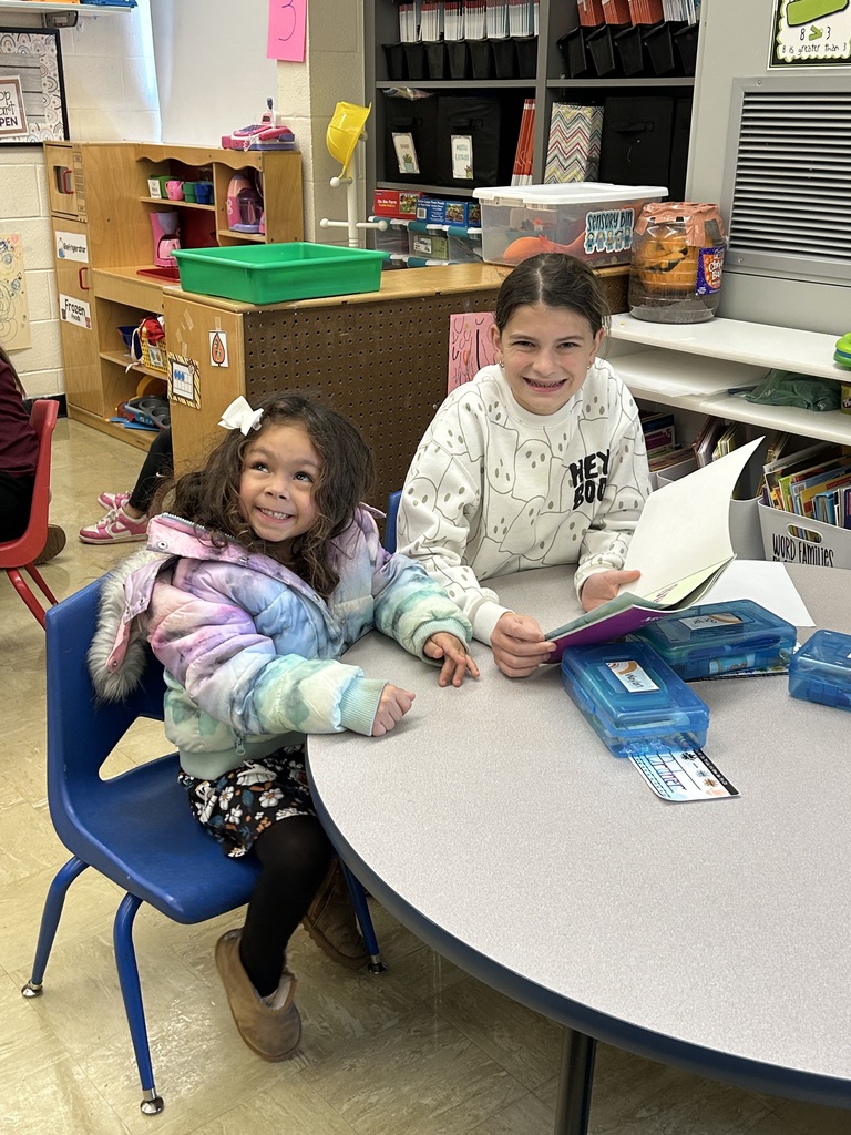 A middle school students is reading a book to a kindergarten student.