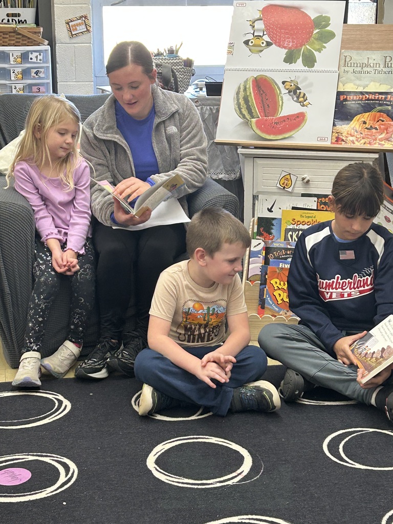 Two middle school students are reading books to two kindergarten students.