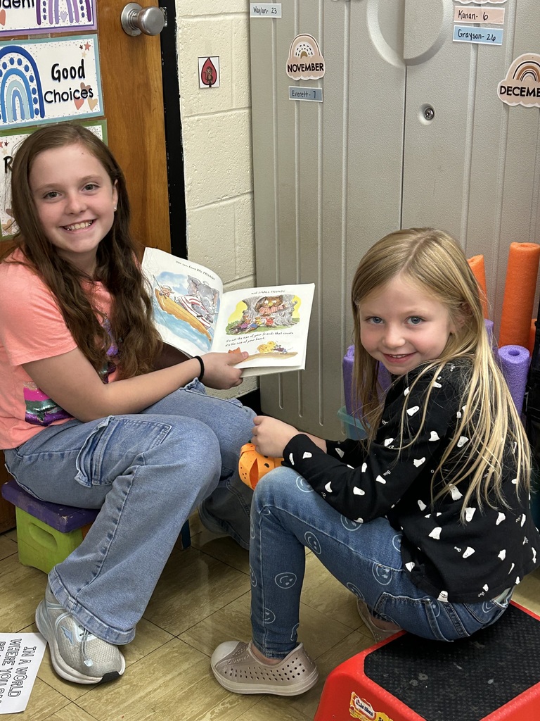 A middle school students is reading a book to a kindergarten student.