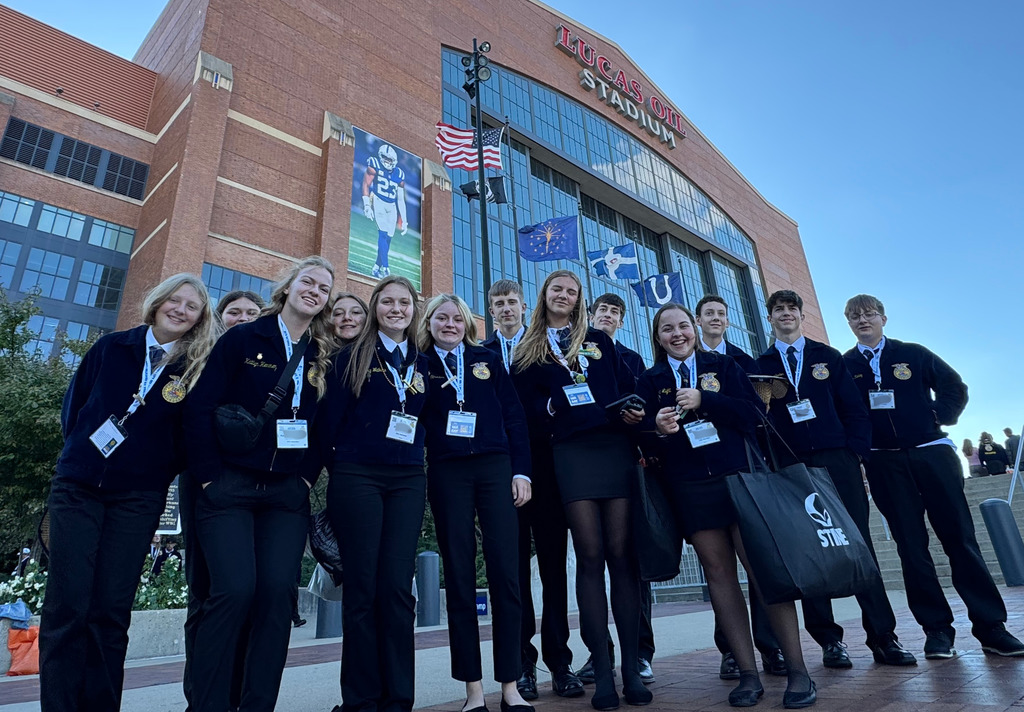 The group is standing in front of Lucas Oil Stadium.