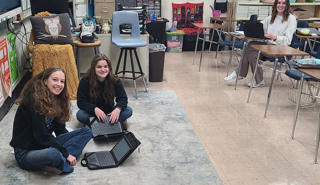 Students are sitting at desks and on the floor. They are evaluating data.
