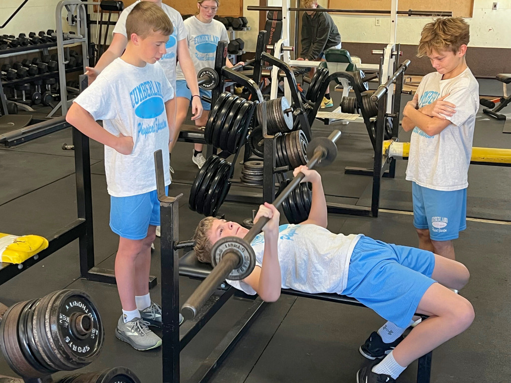 A student is doing the bench press. Two other students are spotting that student.