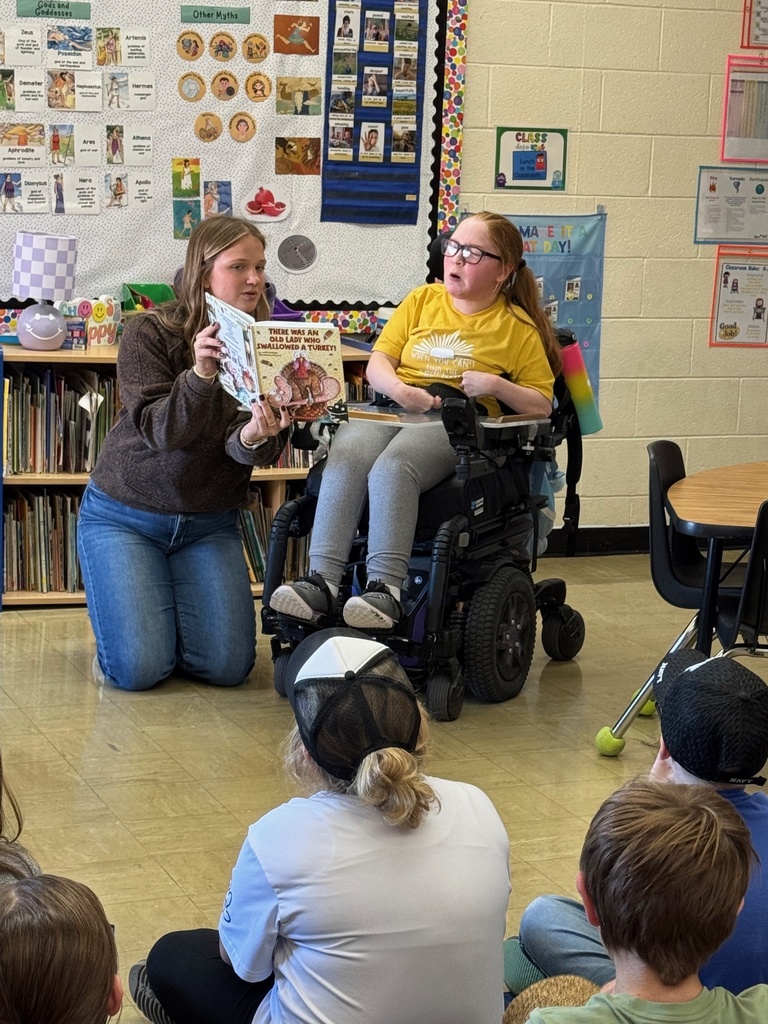 Miss Nevaeh is reading the story to the class. The teacher is holding the book. 