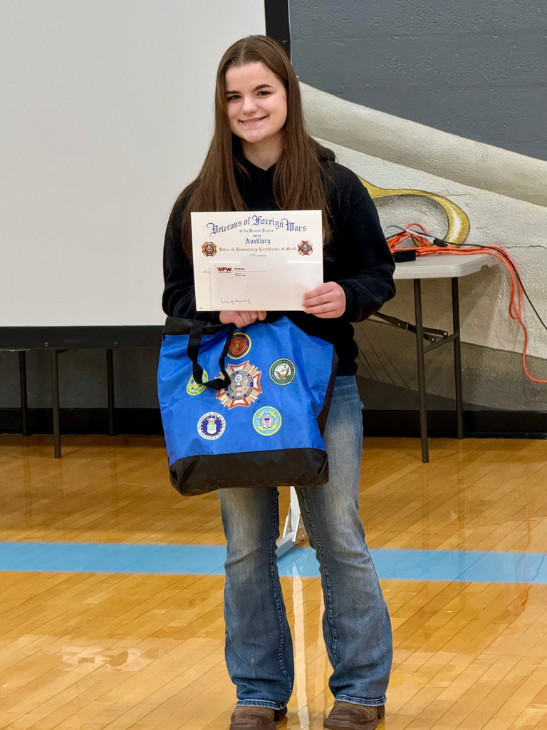 The high school student is standing with her awards for the Patriots Pen essay.