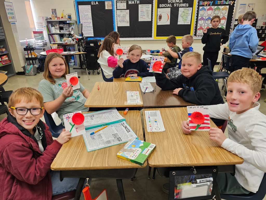 Students pictured are showing their cards to veterans. They have a poppy on the front. They say thank you for your service.