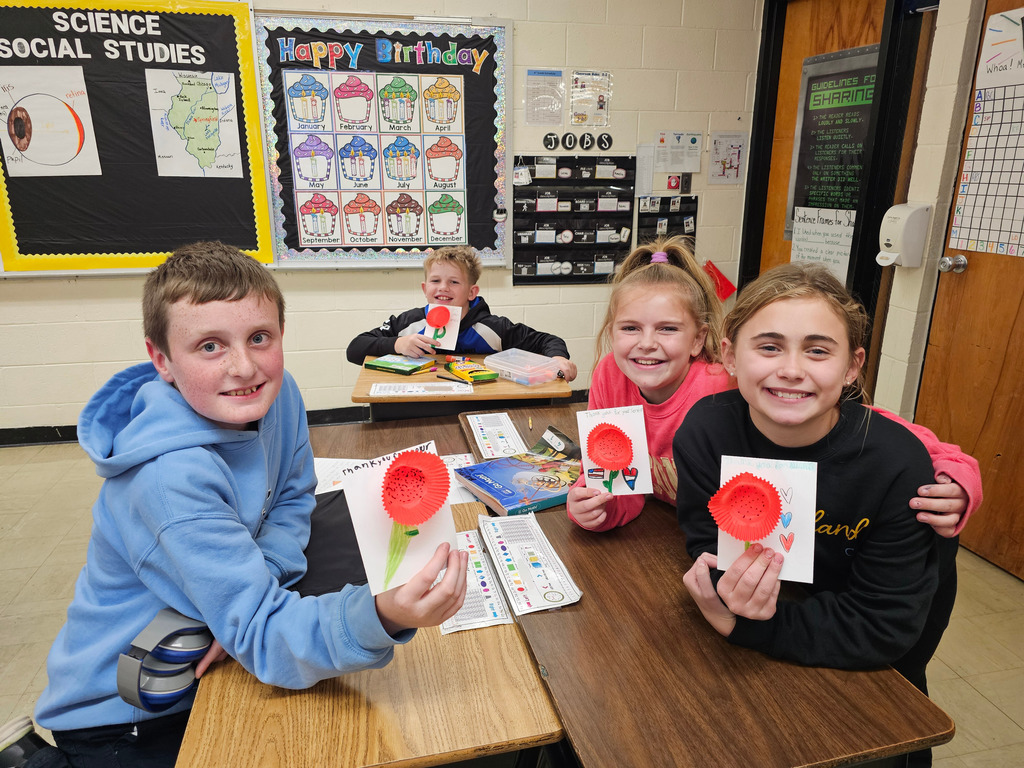 Students pictured are showing their cards to veterans. They have a poppy on the front. They say thank you for your service.
