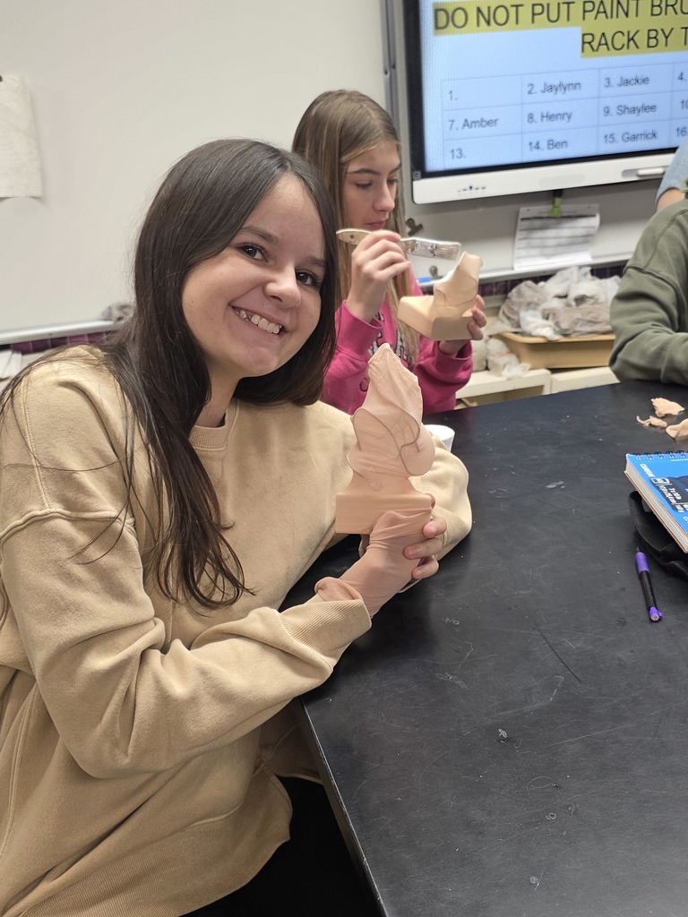 A student is holding her sculpture. Pantyhose is covering wire.