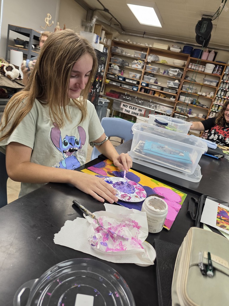 A student is painting her altered painting. The colors are purple and pink.