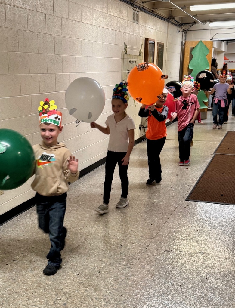 The students are parading through the hallways. They are holding their balloons up for everyone to see. The balloons are decorated in animal designs. 