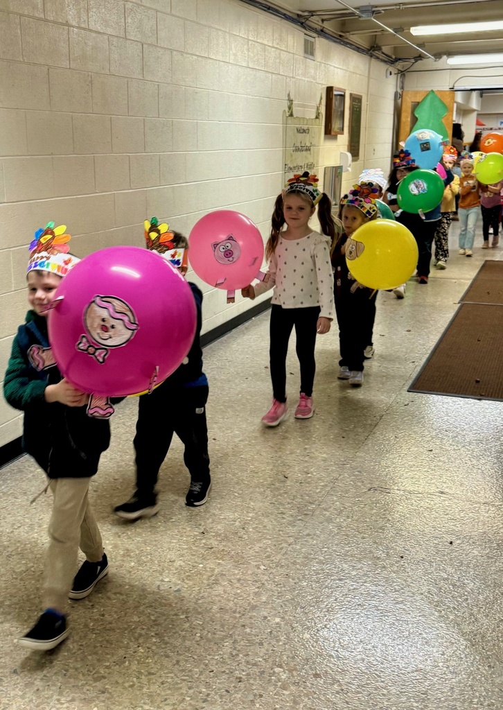 The students are parading through the hallways. They are holding their balloons up for everyone to see. The balloons are decorated in animal designs. 