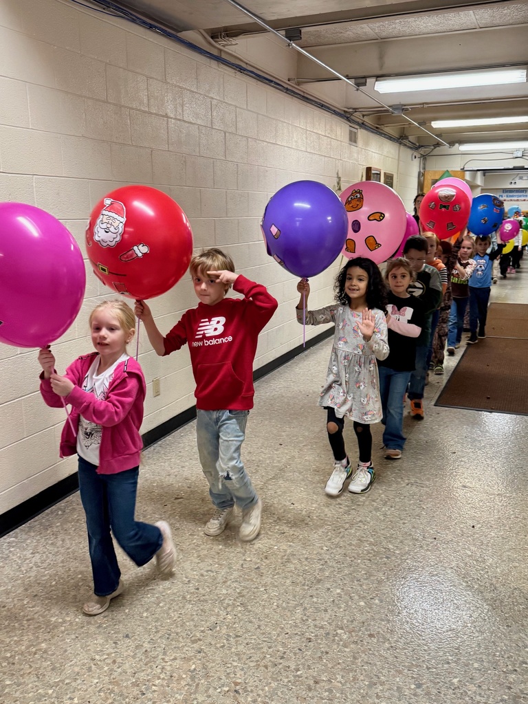The students are parading through the hallways. They are holding their balloons up for everyone to see. The balloons are decorated in animal designs. 