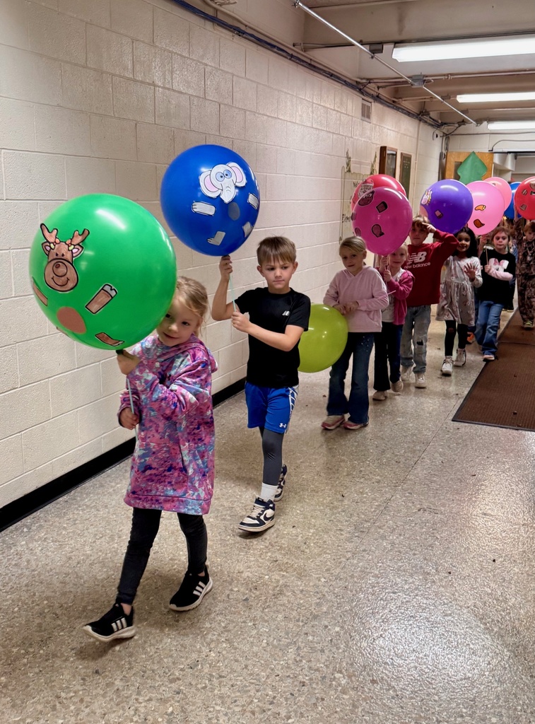 The students are parading through the hallways. They are holding their balloons up for everyone to see. The balloons are decorated in animal designs. 
