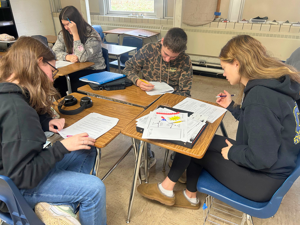 Students are sitting at desks. They are writing in their packets.