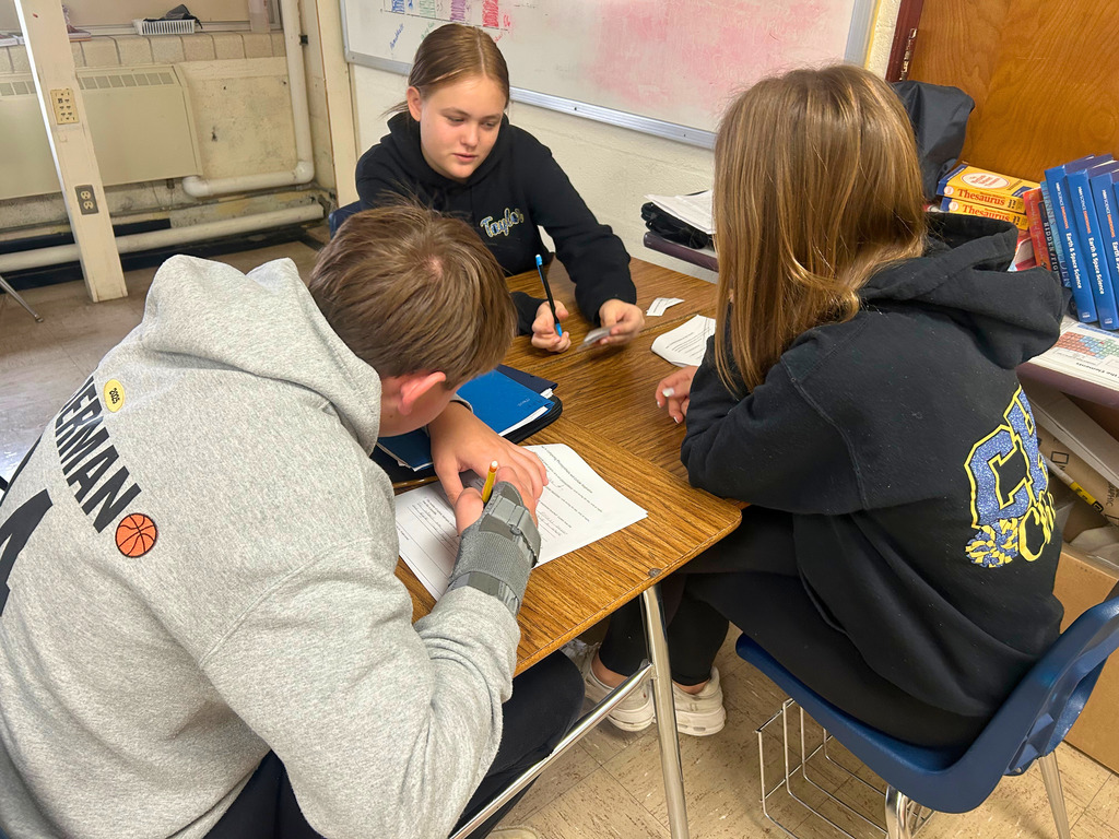 Students are sitting at desks. They are writing in their packets.