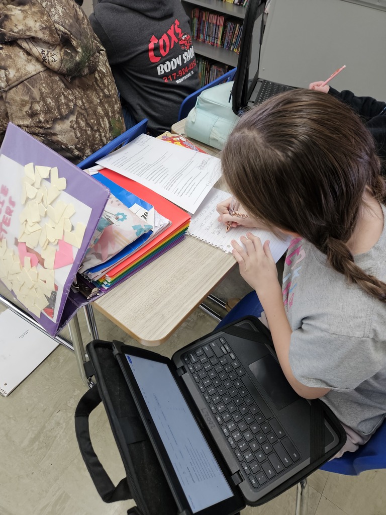 A student is sitting at a desk. She is writing a poem. 