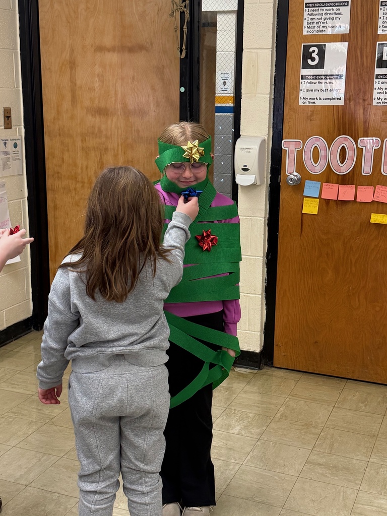 The students are in a line to add an ornament (a bow) to the Christmas tree (student).
