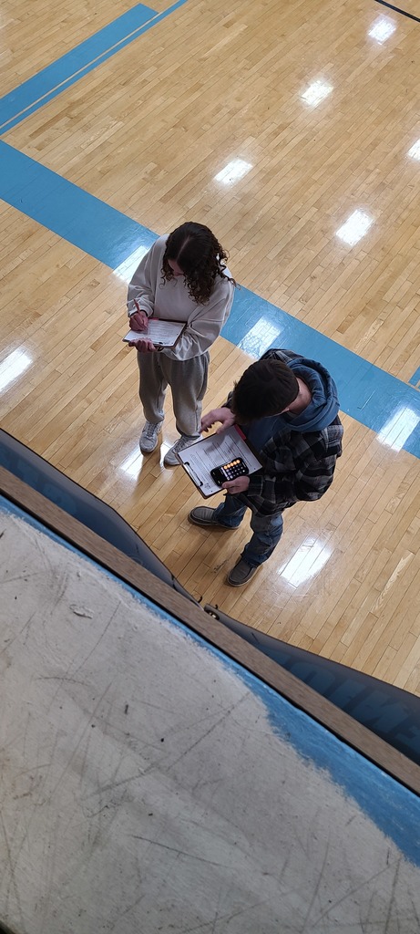 Students are calculating their Barbie data using clipboards and calculators.
