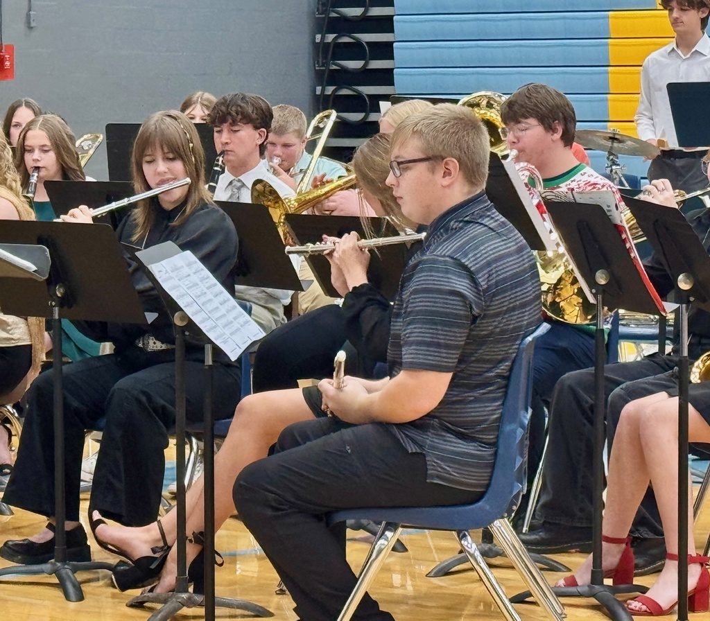 The image shows the woodwind section of the band playing from music on a music stand.