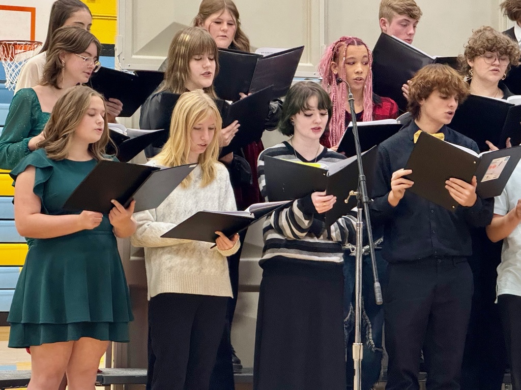 The image shos a third of the choir on the rafters singing from a black binder.
