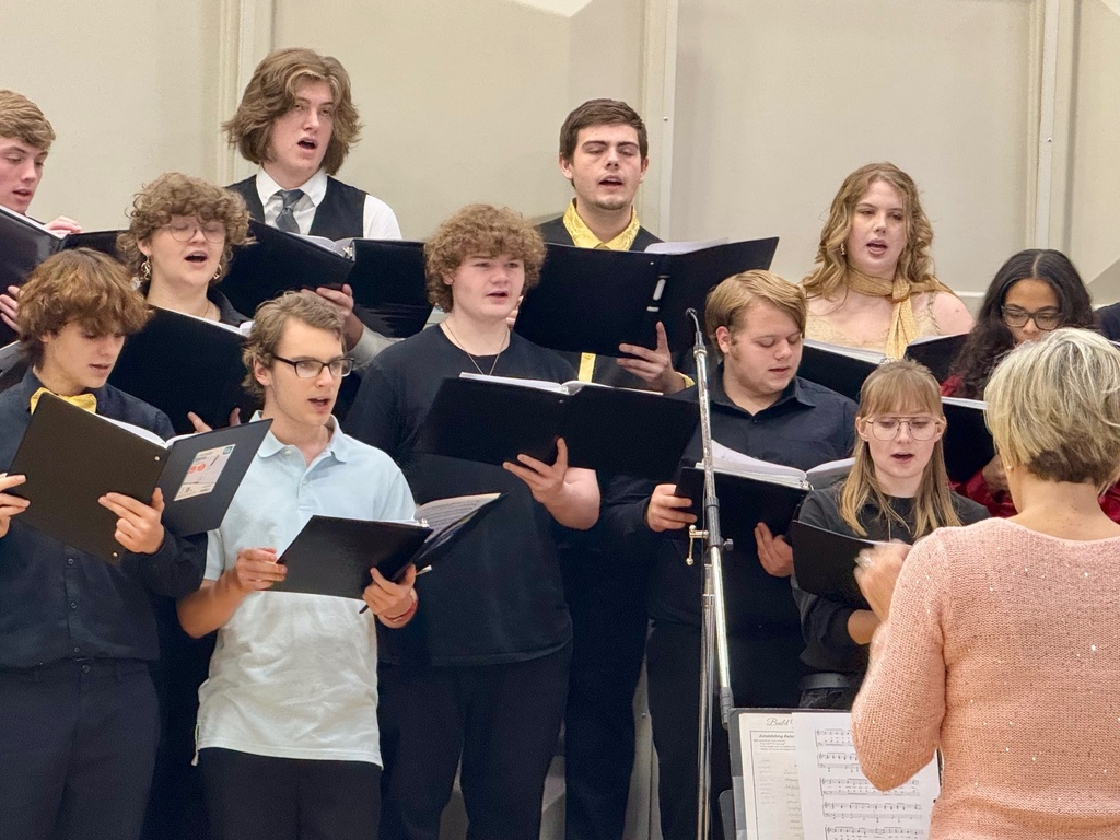 The image shos a third of the choir on the rafters singing from a black binder.