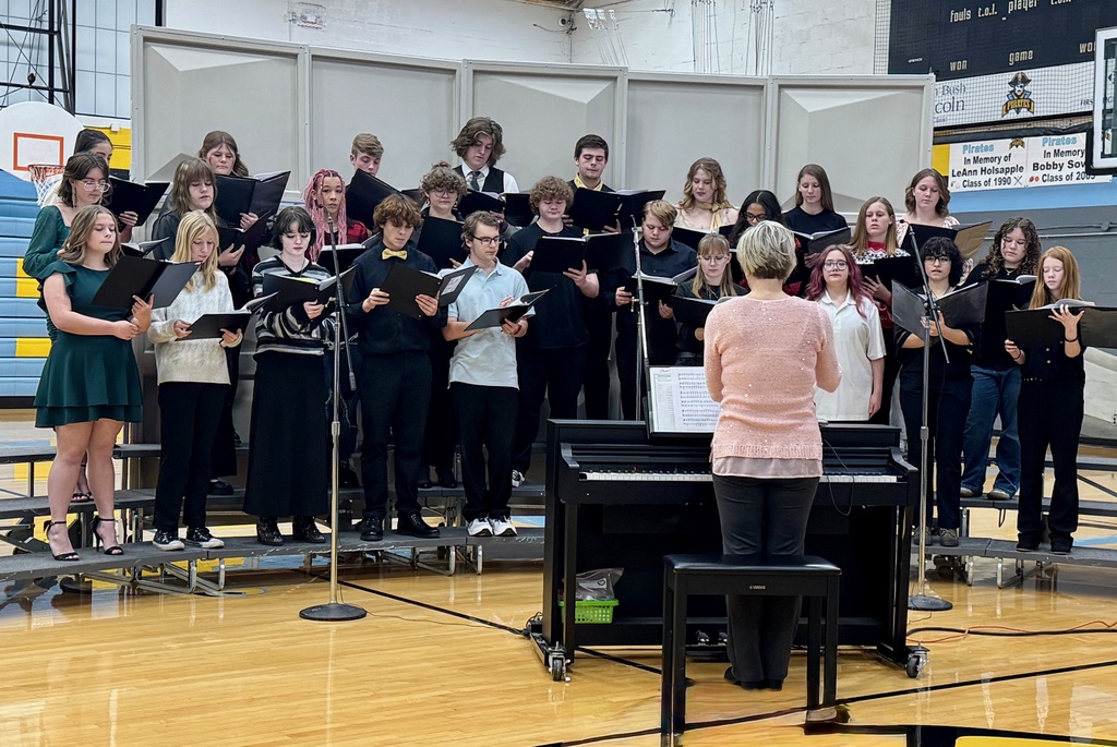 The image shos the entire choir on the rafters singing from a black binder.